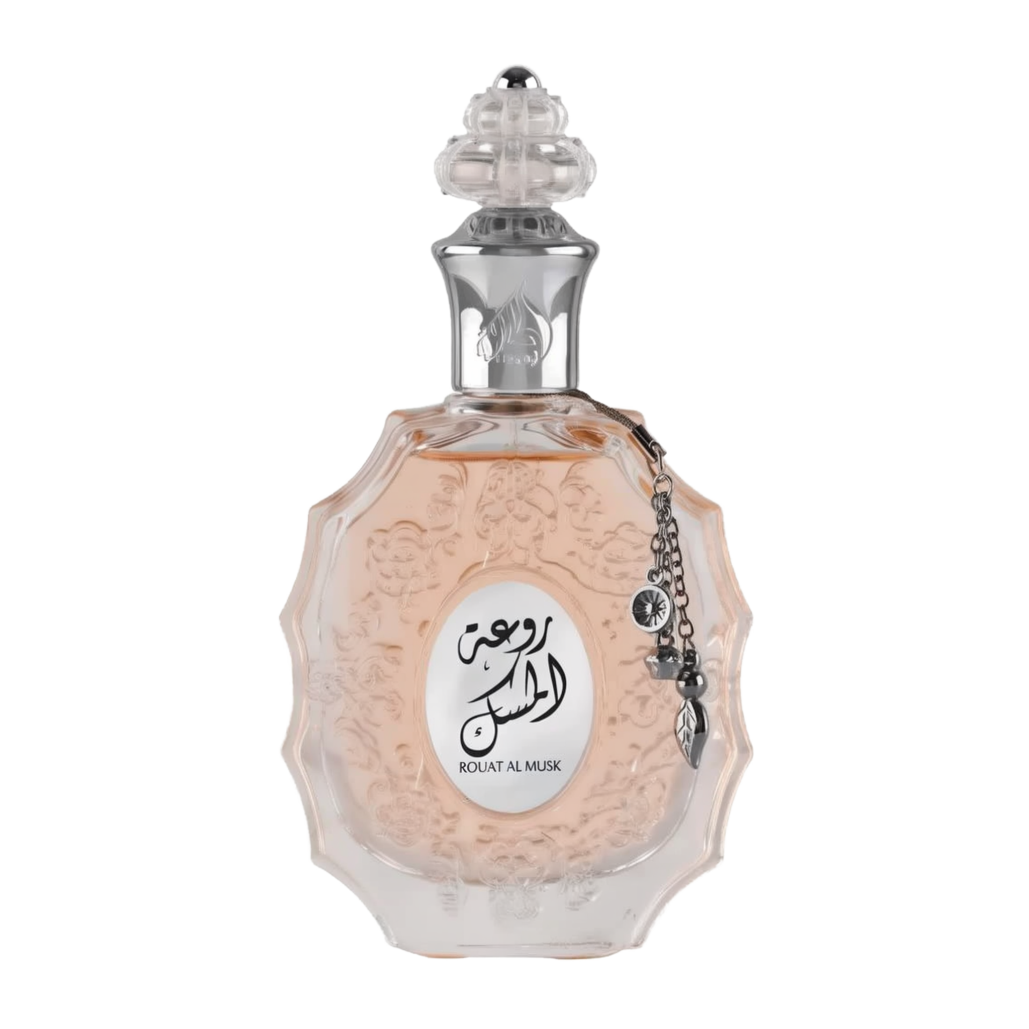 The image shows a decorative perfume bottle: The bottle has an ornate, multi-faceted glass design with a textured surface and a pale pink tint, suggesting a delicate fragrance within. It features a clear glass stopper with an intricate cut pattern on top. A metallic silver chain with a charm and a small black stone is attached to the neck of the bottle. The front of the bottle displays a white oval label with Arabic calligraphy and the name "ROUAT AL MUSK" in Roman characters below.
