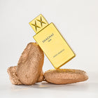 Gold Shaghaf Oud perfume bottle with two gold rocks on a light gray background
