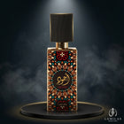 Lattafa Ajwad perfume bottle with a multicolored geometric pattern, black cap, and gold trim, on a smoky dark platform.