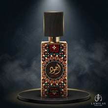 Lattafa Ajwad perfume bottle with a multicolored geometric pattern, black cap, and gold trim, on a smoky dark platform.