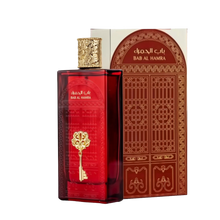 The image features a rectangular perfume bottle with a deep red hue and a highly ornate gold cap. On the bottle is an embossed golden emblem in the shape of a key, which adds to the luxurious appearance of the product. Accompanying the bottle is a box with Arabic and English text, "??? ?????? / BAB AL HAMRA," likely the name of the fragrance.  The product appears to be of Middle Eastern origin and suggests a fragrance with a rich and exotic scent.