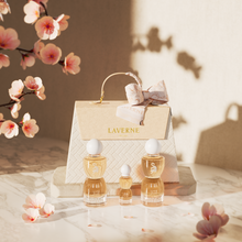 Laverne Sense Forever perfume trio arranged before a textured gift bag, with soft pink blossoms and warm light.