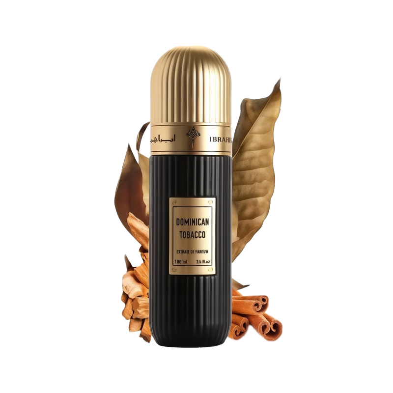 A cylindrical black perfume bottle with a gold cap, labeled "DOMINICAN TOBACCO" in white text, and "Extrait de Parfum 100 ml 3.4 fl.oz" in smaller white text. It has an Arabic inscription and the brand name "IBRAHEEM AL QURASHI" at the top. The bottle is presented in front of two large dried tobacco leaves and rests on a surface with scattered cinnamon sticks. The background is white, emphasizing the product.