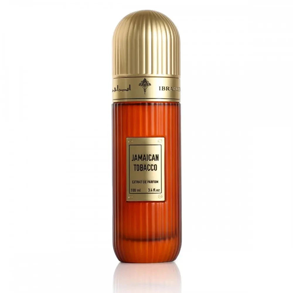 his is an image of a tall, cylindrical perfume bottle with a golden cap, featuring an amber-colored glass body. The bottle is labeled "Jamaican Tobacco" and "Extrait de Parfum", with a volume indication of "100 ml / 3.4 fl.oz." The label is placed on a gold plaque that matches the cap, and the Ibraheem Al Qurashi logo is visible at the top of the bottle.