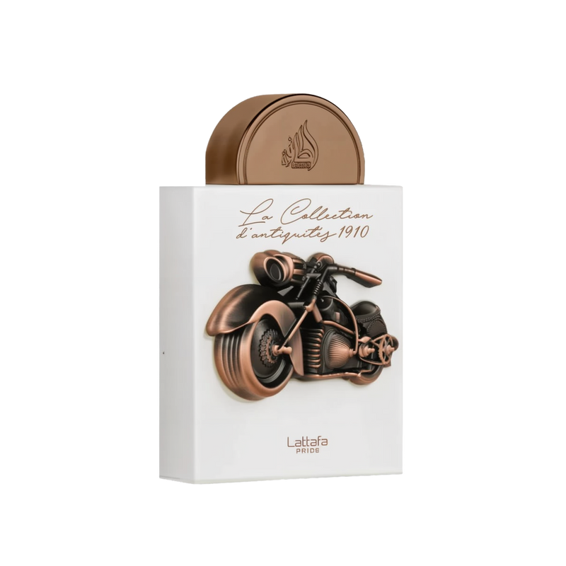 The image depicts a perfume box from "La Collection d'antiquité 1910" by Lattafa Pride. The box is white and features a copper-toned three-dimensional sculpture of a vintage motorcycle. The text "La Collection d'antiquité 1910" is elegantly written in cur