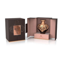 A product shot of Le Falcone Niche Collection’s “Turath Intense” perfume against a white background: on the left is a closed, matte dark‑brown rectangular gift box with a copper foil plaque bearing Arabic calligraphy above the words “Turath Intense” and the Le Falcone logo. On the right, the box is open to reveal a heart‑shaped amber glass bottle resting on a raised copper‑pink interior platform.