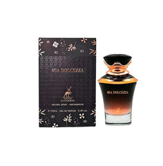A rectangular black box with gold floral accents labeled “Mia Dolcezza” by Maison Alhambra stands beside a matching black-to-gold ombré glass perfume bottle with a decorative cap, displaying the same product name and brand.