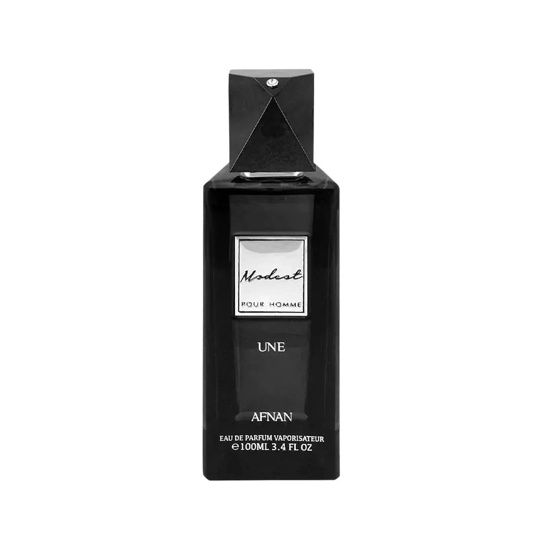 The image is of a black perfume bottle for "Modest UNE" by Afnan Perfumes. The bottle has a sleek, rectangular shape with a black cap and a diamond-like embellishment on the top. The label on the bottle is white with black lettering that reads "Modest" in