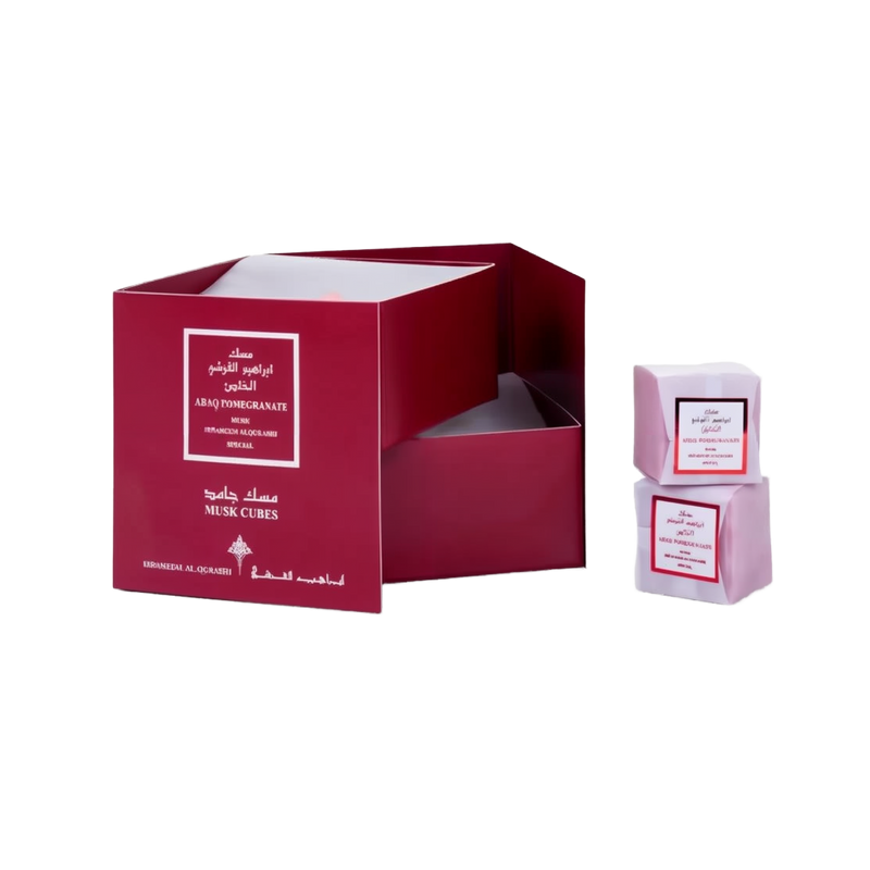 Open maroon Ebraheem Al Qurashi Pomegranate Musk Cubes gift set packaging next to two pink wrapped solid perfume cubes.ebraheem-al-qurashi-pomegranate-musk-cubes-packaging.jpg