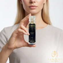 Woman holding the black Nasmaat perfume bottle filled with shimmering gold liquid