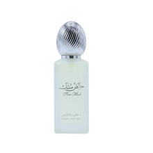  The image features a bottle of hair mist with a pastel-colored body, likely a frosted glass with a light blue tint. The cap is metallic silver with a ribbed texture, resembling a polished metal. On the bottle, there is Arabic calligraphy above the English words "Pure Musk." Below this, in a smaller font, the text "FRESH HAIR MIST" is visible. 
