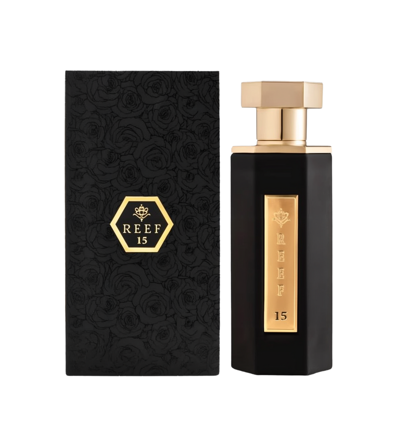 A luxurious bottle of Reef 15 perfume by Reef Perfumes, shown beside its matching box. The perfume bottle has a tall, angular design in sleek black, featuring a vertical gold panel engraved with 'REEF 15' and a crown emblem. It is topped with a polished hexagonal gold cap. The black box is adorned with an embossed floral rose pattern and a gold hexagon emblem containing the brand name and number, matching the elegant and refined look of the bottle.