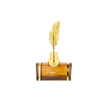 The image features an elegant, transparent amber-colored perfume bottle with a distinctive golden feather as its cap. The bottle has a robust, rectangular shape with rounded shoulders, and a gold neck that supports the feather-shaped cap, adding a luxurious touch to the design. On the front of the bottle, there is script text which appears to be a brand or perfume name, possibly in Arabic, and the word "Resala" in a stylized font.