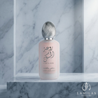 Lamila's Rouat Al Musk Fresh Hair Mist, a frosted pink bottle with a detailed silver cap, displayed on a marble pedestal.