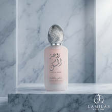 Lamila's Rouat Al Musk Fresh Hair Mist, a frosted pink bottle with a detailed silver cap, displayed on a marble pedestal.