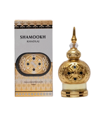 The image shows a product called "Shamookh" by Khadlaj, which is a concentrated perfume oil. The product is presented in an ornate 20ml bottle with a spherical design. The bottle is gold with intricate patterns and a decorative, pointed cap, giving it a luxurious and elegant appearance. The packaging box complements the bottle's design with a gold and black theme, featuring the product name "Shamookh" in bold letters.