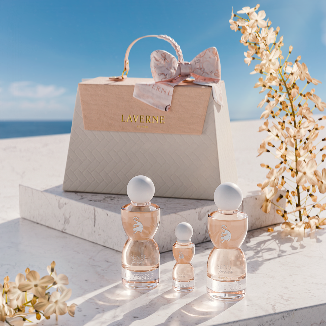 Laverne Sense Forever perfume trio set before a beige gift bag, styled with white blossoms under a clear blue sky.