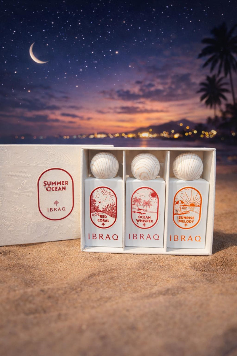 Summer Ocean gift set of three white perfumes with wooden caps rests on sand under a starry twilight sky.
