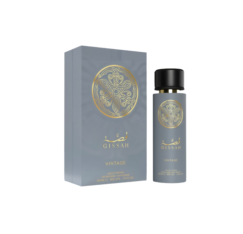 The image of “Gissah Vintage” perfume against a white background: on the left, a tall, matte-gray rectangular gift box featuring a large, circular gold-foil arabesque emblem above Arabic calligraphy and the word “Gissah,” with “Vintage” printed below in gold lettering and product details at the bottom.