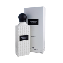 A refined bottle of White Regent Diamond Eau De Parfum by Ibraheem Al-Qurashi, shown next to its matching box. The bottle features a matte white finish with a quilted diamond pattern and a rectangular black label reading 'WHITE REGENT DIAMOND' in white text. It is topped with a smooth, matte black spherical cap. The box mirrors the minimalist white design with a matching black label and understated branding along the bottom.