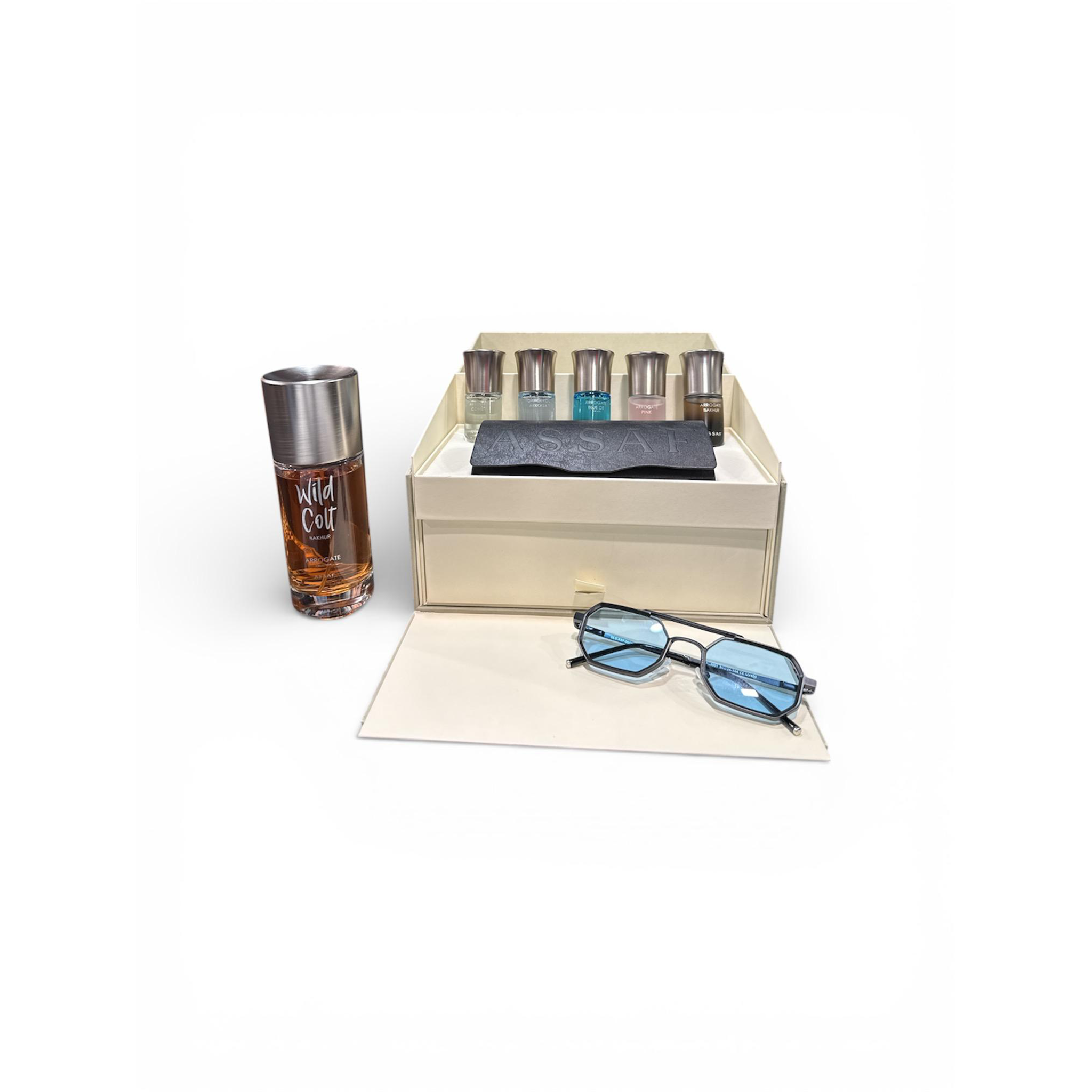 Assaf Wild Colt Bakhur gift set featuring an amber Wild Colt bottle, open presentation box with mini perfumes, and a pair of blue-tinted sunglasses placed in front.
