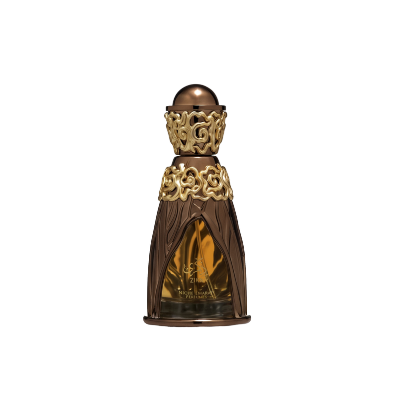 A luxurious perfume bottle for 'Zikra' from the Niche Emarati collection by Lattafa. The bottle has an ornate golden and bronze design, featuring intricate floral patterns at the neck and base. The body of the bottle is translucent, showcasing the amber-c