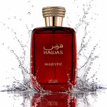 A red glass perfume bottle labeled 'HAWAS MAJESTIC' with a gold cap, surrounded by water splashes on a white background.